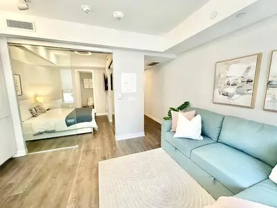 a living room with a blue couch and a bedroom at Condo in Yorkville - Newly Furnished Luxury Unit in Toronto
