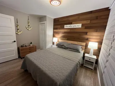 a bedroom with a bed and a wooden wall at The Luxe Lodge in Algonquin Highlands