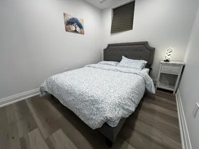 a bedroom with a bed with a blue comforter at Cozy 2 Bedrooms Modern Basement Suite with Private entrance, Kitchen and parking in Mississauga