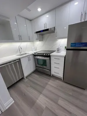 a kitchen with white cabinets and stainless steel appliances at Cozy 2 Bedrooms Modern Basement Suite with Private entrance, Kitchen and parking in Mississauga