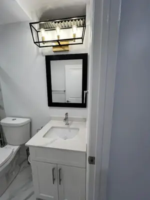a white bathroom with a sink and a mirror at Cozy 2 Bedrooms Modern Basement Suite with Private entrance, Kitchen and parking in Mississauga