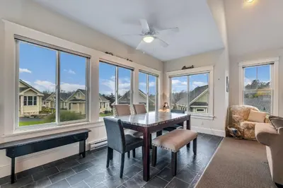 a dining room with a table and chairs and windows at The Meadowlark - 115 Butternut in Cherry Valley