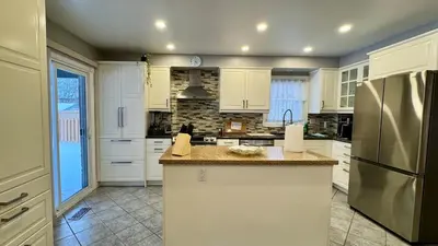 a kitchen with white cabinets and a stainless steel refrigerator at Luxury Modern Retreat with Sauna & Modern Amenities in Mississauga