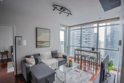 a living room with a couch and a table at 3BR Urban Gem with Scenic Balcony Views in Toronto
