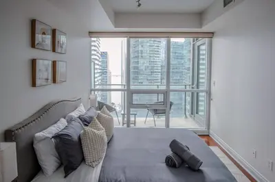 a bedroom with a bed and a large window at 3BR Urban Gem with Scenic Balcony Views in Toronto
