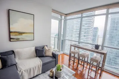a living room with a couch and a table with chairs at 3BR Urban Gem with Scenic Balcony Views in Toronto