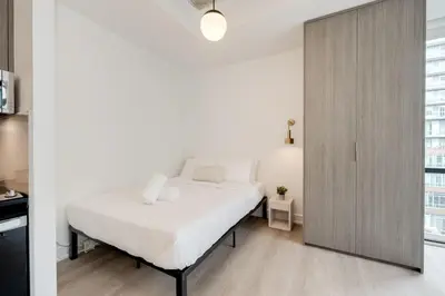 a bedroom with a white bed and a sliding door at Studio Gem in the lovely Waterfront Communities in Toronto