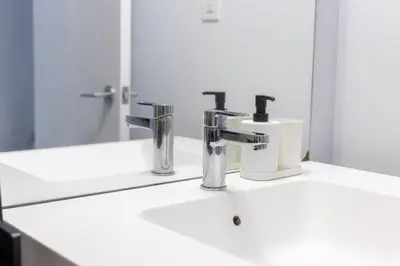 a bathroom sink with two faucets and a mirror at Exquisitely Furnished 1BR Suite in DWTN Toronto in Toronto
