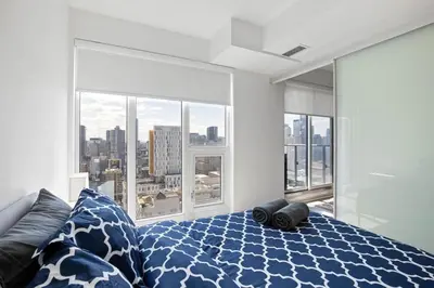 a bedroom with a bed with a view of a city at Downtown 2 bedroom Condo with Private Balcony in Toronto