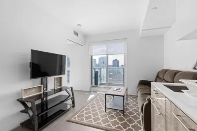 a living room with a couch and a flat screen tv at Downtown 2 bedroom Condo with Private Balcony in Toronto