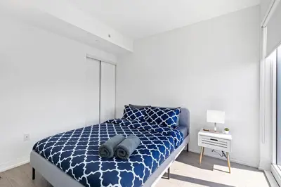a bedroom with a bed with a blue comforter at Downtown 2 bedroom Condo with Private Balcony in Toronto