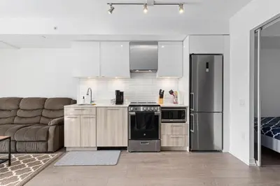 a kitchen with a stainless steel refrigerator and a couch at Downtown 2 bedroom Condo with Private Balcony in Toronto