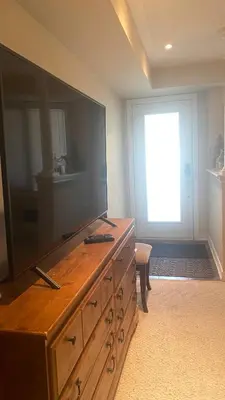 a living room with a large flat screen tv on a dresser at Toronto downtown Woodbine beaches private cozy room in Toronto