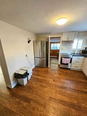 a kitchen with a refrigerator and a wooden floor at Spacious 2-bedroom ground floor unit near beach in Cobourg