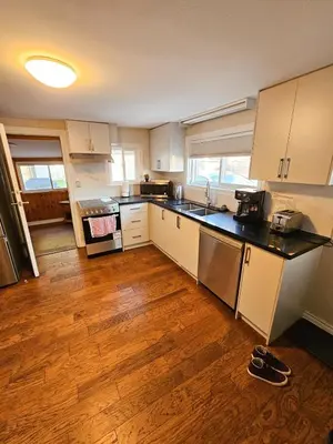 a kitchen with white cabinets and a wooden floor at Spacious 2-bedroom ground floor unit near beach in Cobourg
