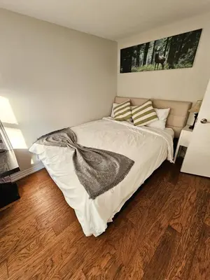 a bedroom with a large bed with a wooden floor at Spacious 2-bedroom ground floor unit near beach in Cobourg