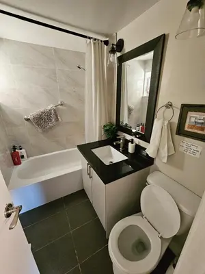 a bathroom with a toilet and a sink and a tub at Spacious 2-bedroom ground floor unit near beach in Cobourg