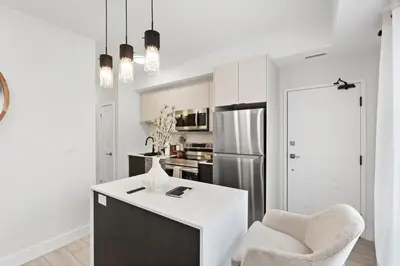 a kitchen with a white counter and a chair and a refrigerator at Cozy 2BR Suite with Parking & Close to Niagara Falls and Sleeps 6 Guests in Niagara Falls