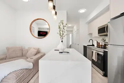 a white living room with a couch and a table at Cozy 2BR Suite with Parking & Close to Niagara Falls and Sleeps 6 Guests in Niagara Falls