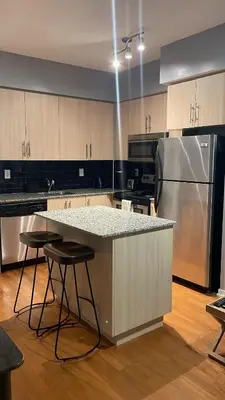 a large kitchen with a counter and a refrigerator at 1 BD and Den at Scotiabank Arena in Toronto
