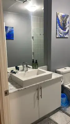 a bathroom with a white sink and a mirror at 1 BD and Den at Scotiabank Arena in Toronto