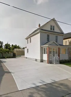 a white house with a driveway in front of it at Ultra Close to Clifton Hill and the Falls & Wonderful Free Breakfast Delivered Daily in Niagara Falls