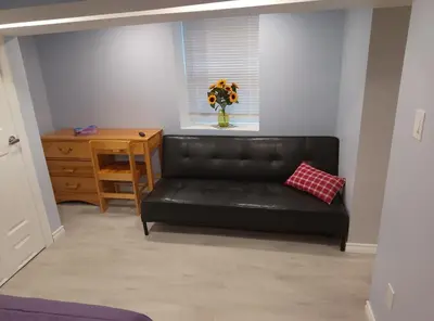 a black leather couch in a living room with a vase of flowers at Midtown Toronto suite in Toronto