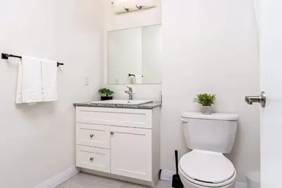 a white bathroom with a toilet and a sink at DT High Rise Condo w Private Patio and View in Kitchener