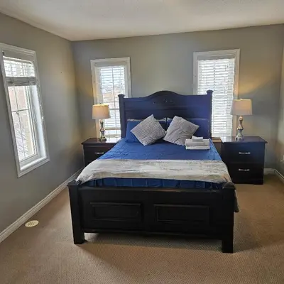 a bedroom with a blue bed with two windows at Exquisite Junior Bedroom in Brampton