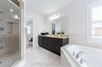 a bathroom with a tub and a shower and a sink at Beautiful 4 bed 3 master bedrooms-pvt washrooms in Brampton
