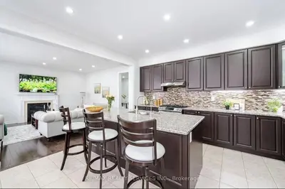 a kitchen with brown cabinets and a living room at Beautiful 4 bed 3 master bedrooms-pvt washrooms in Brampton