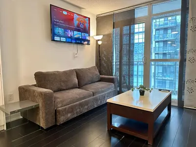 a living room with a couch and a tv at Spacious & Central 1 bdrm 2 real beds in Toronto