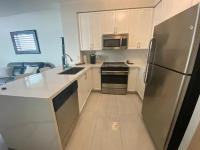 a kitchen with white cabinets and a stainless steel refrigerator at Cityscape in Mississauga