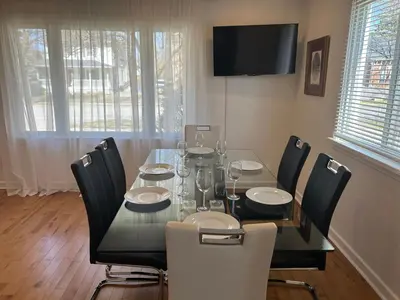 a dining room with a table with chairs and a television at Serenity Charm - Walk in Town, Shaw, Hottub in Niagara on the Lake