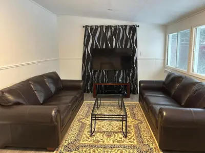 a living room with two leather couches and a television at Serenity Charm - Walk in Town, Shaw, Hottub in Niagara on the Lake