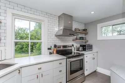 a kitchen with white cabinets and a stove top oven at Boutique Quality Home Downtown by the Shaw in Niagara on the Lake