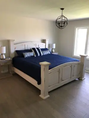 a bedroom with a large bed with blue sheets and pillows at Boutique Quality in Old Towne with Hot Tub in Niagara on the Lake