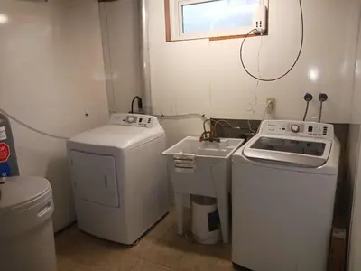 a small laundry room with a washer and a sink at Cosy Romantic and Cost Effective Stay in Kitchener in Kitchener