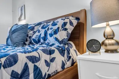 a bed with a blue and white comforter and a clock at Spacious 4BR Home with Parking in Richmond Hill