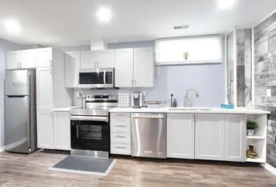 a kitchen with white cabinets and stainless steel appliances at Deluxe Apartment in Caledon