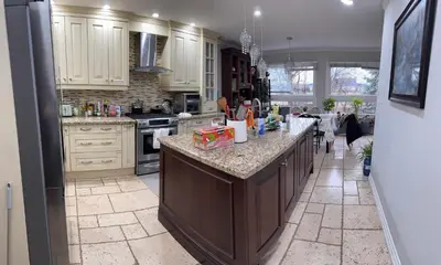 a kitchen with white cabinets and a large island at Large private room in Mississauga