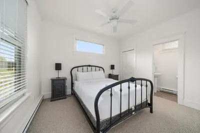 a white bedroom with a bed and a ceiling fan at The Finch - 59 Butternut in Cherry Valley