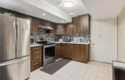 a kitchen with wooden cabinets and a stainless steel refrigerator at Comfortable & Cozy 2BR Hideaway Basement Appartment in Brampton