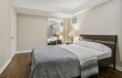 a bedroom with a large bed and a mirror at Comfortable & Cozy 2BR Hideaway Basement Appartment in Brampton