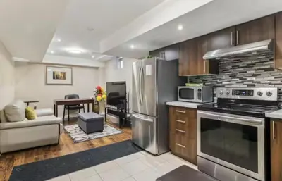 a kitchen with stainless steel appliances and a living room at Comfortable & Cozy 2BR Hideaway Basement Appartment in Brampton