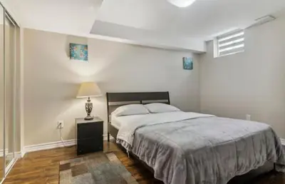 a bedroom with a large bed and a night stand at Comfortable & Cozy 2BR Hideaway Basement Appartment in Brampton