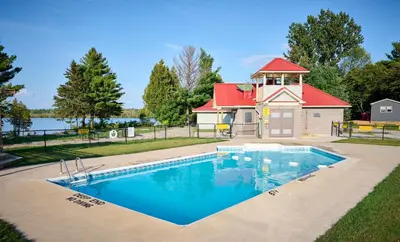 a swimming pool in front of a house with a playground at The Balmoral at Duck Lake in Carden