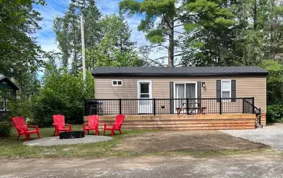 a tiny house with red chairs and a patio at The Balmoral at Duck Lake in Carden
