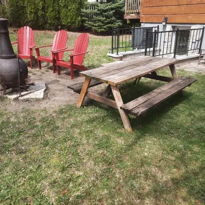 a wooden picnic table and chairs next to a grill at Cottage by the beach in Wasaga Beach