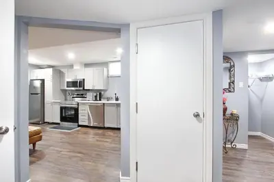 a kitchen with white cabinets and a open door at Deluxe Apartment in Caledon